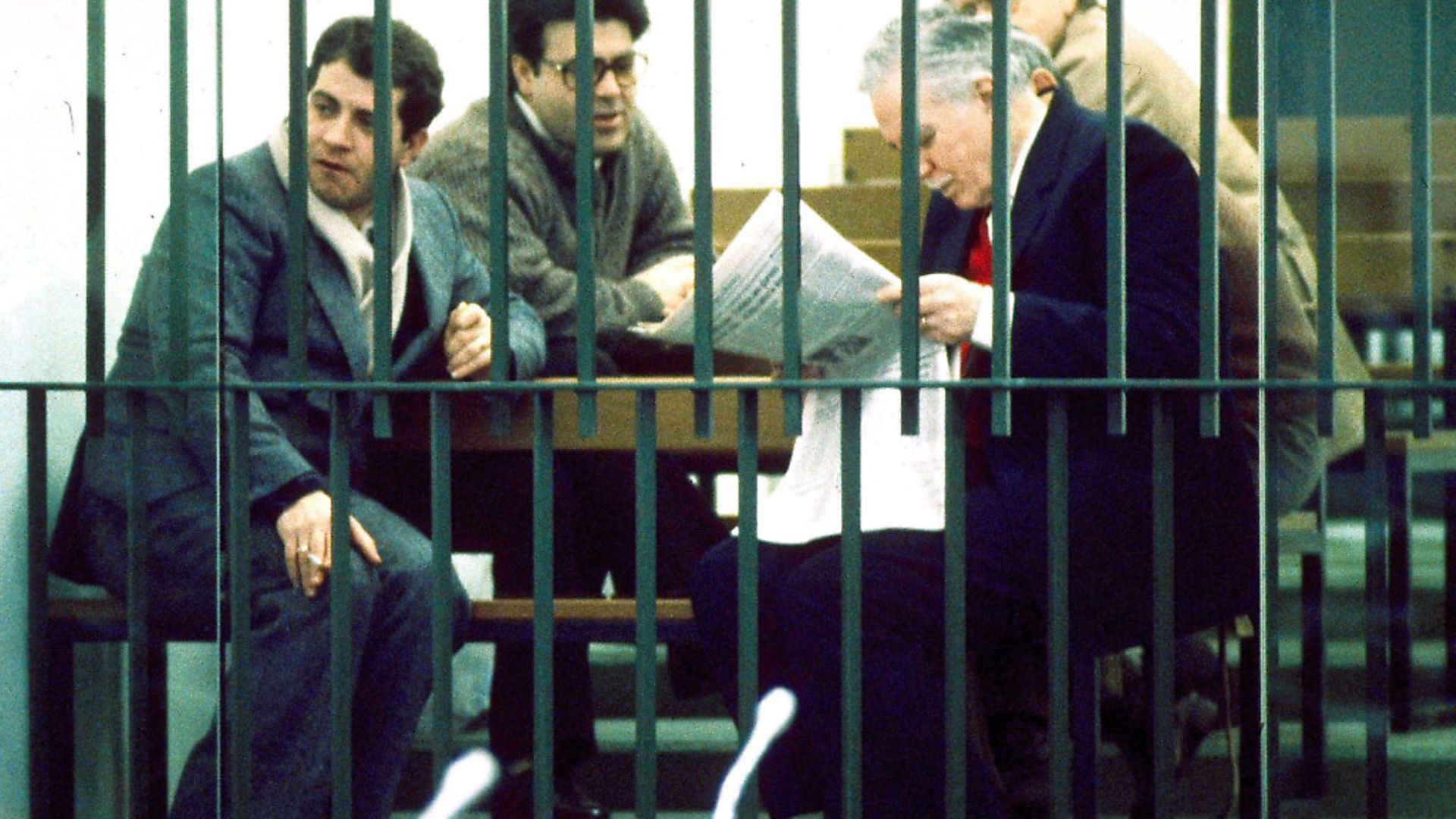 Defendants (Giovanni Falcone, front r) wait behind bars to have their case heard in the Maxi Trial against the Mafia in Palermo. Picture: PA - Credit: Press Association Images