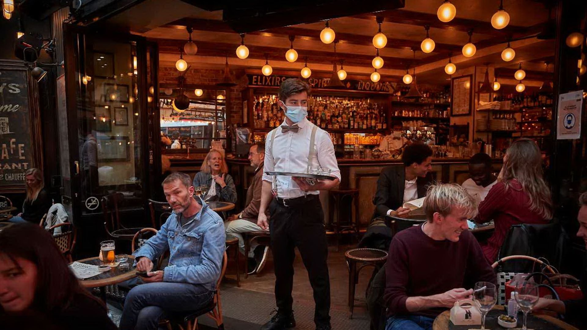 A waiter serving drinkers during the pandemic in Paris - Credit: Kiran Ridley/Getty Images
