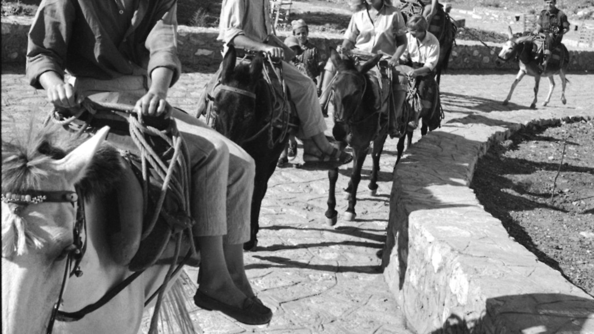 Norwegian expatriate Marianne Jensen (also known as Ihlen) (left), Canadian poet, author, and musician Leonard Cohen, and others rides mules along a stone path, Hydra, Greece, October 1950. Cohen had bought a house on the island earlier in the year; Jensen inspired a number of his songs and poems. (Photo by James Burke/The LIFE Picture Collection via Getty Images/Getty Images) - Credit: The LIFE Picture Collection via