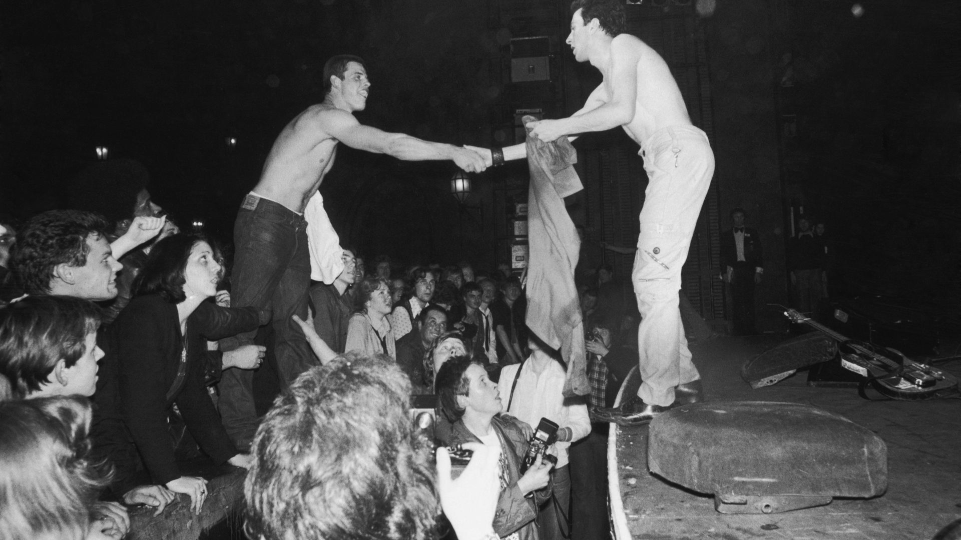 Joe Strummer (1952 - 2002), lead singer of punk rock band The Clash, exchanges shirts with a fan at The Rainbow Theatre, London - Credit: Getty Images