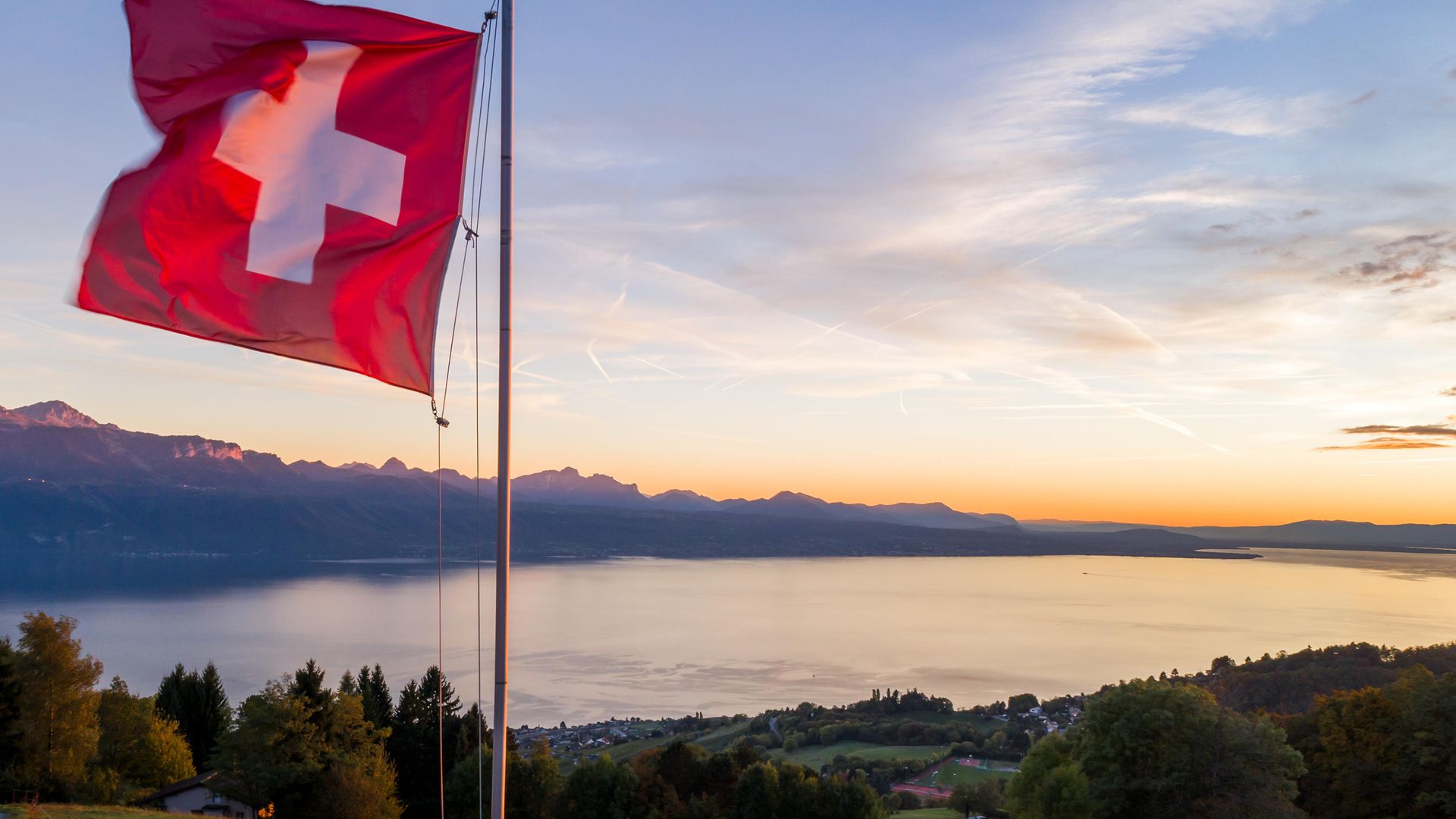 Flying the flag for languages.... a Swiss flag is seen floating at sunset above Lake Geneva - Credit: AFP via Getty Images