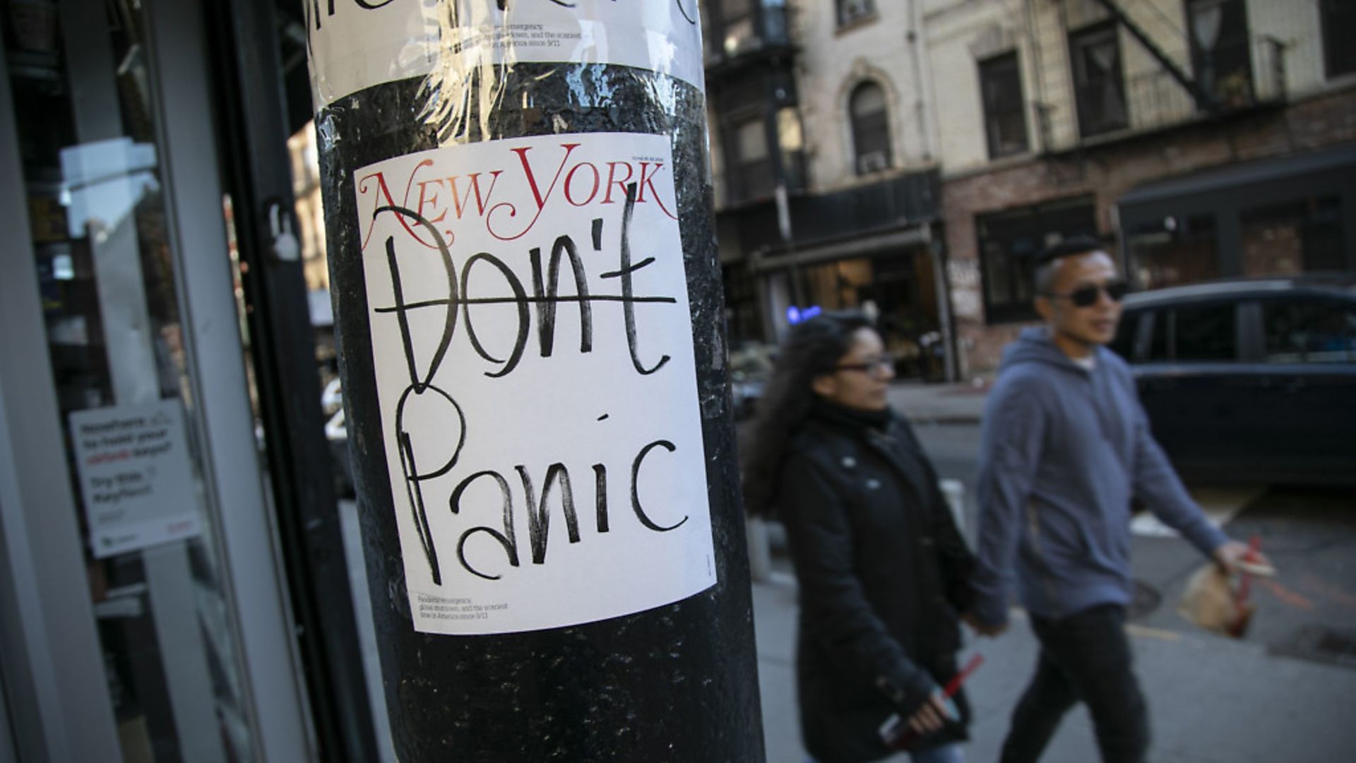 People walk past a convenient store where the latest cover of a magazine is stuck on a pillar outside of it in New York. (AP Photo/Wong Maye-E) - Credit: AP