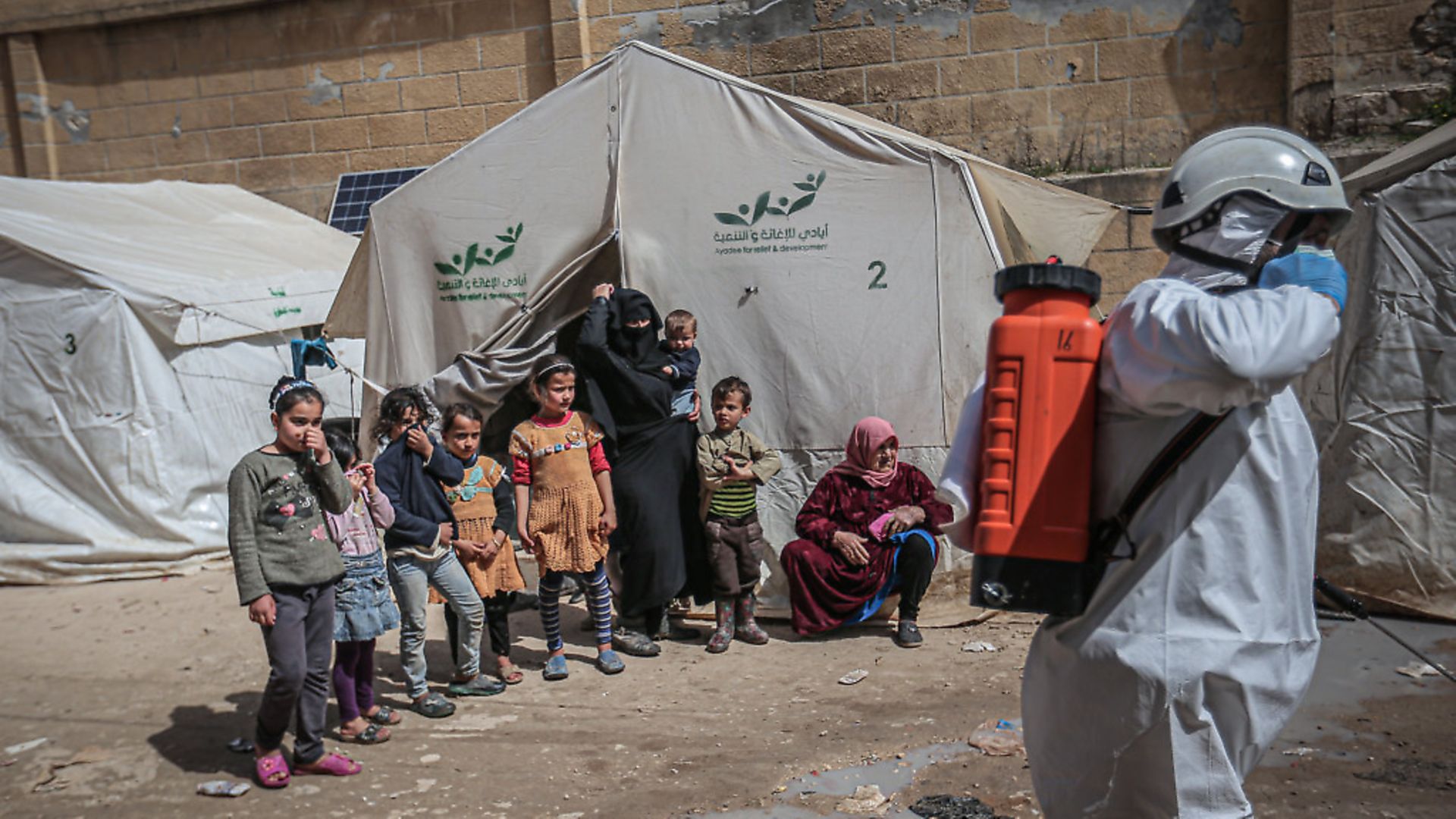 IDLIB, SYRIA - MARCH 24: Members of the Syrian Civil Defence (White Helmets) disinfect  buildings and tents where families live collectively as a preventive measure against coronavirus (Covid-19) pandemic in Idlib, Syria on March 24, 2020. (Photo by Muhammed Said/Anadolu Agency via Getty Images) - Credit: Anadolu Agency via Getty Images
