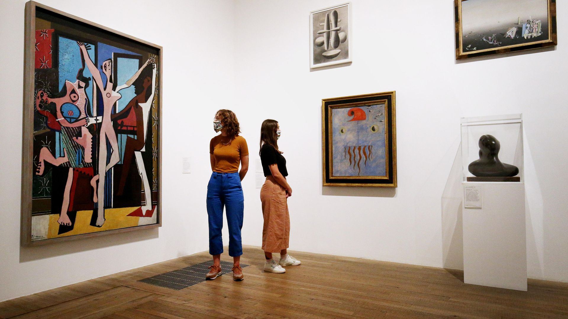 Members of staff wear artwork inspired masks as they look at works including Picasso's 'The Three Dancers' (left) at the Tate Modern - Credit: PA