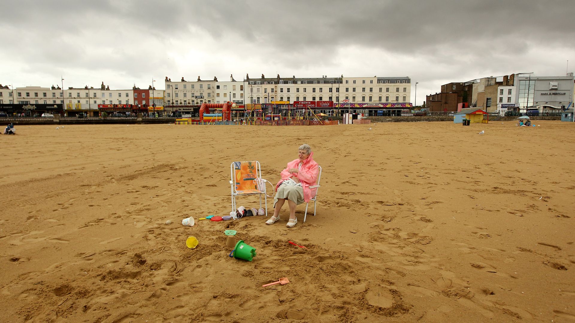 A beachgoer sits in a deckchair below grey clouds in Margate - Credit: Getty Images