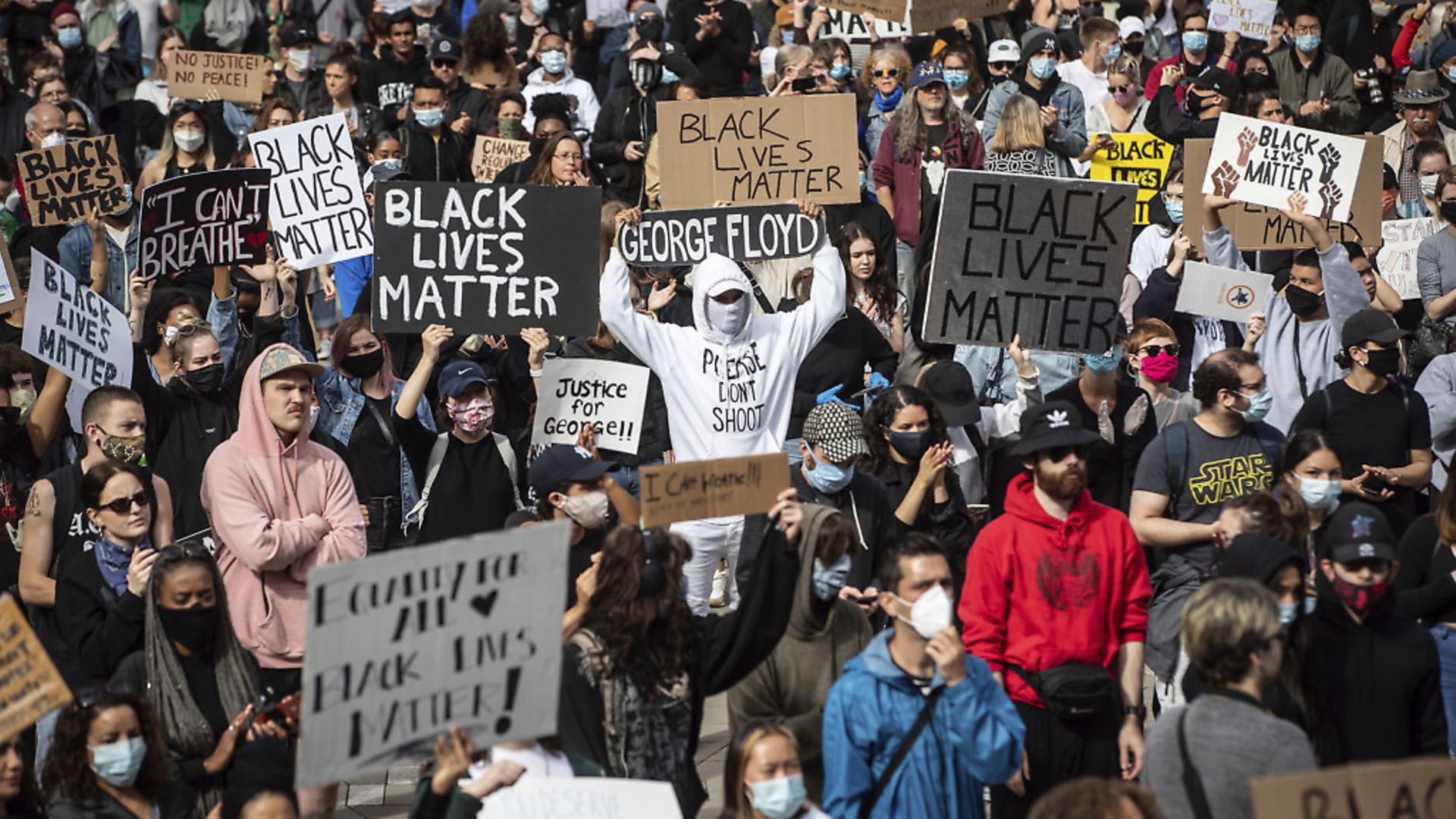 A man holds a skateboard bearing George Floyd's name above his head as thousands of people gather for a peaceful demonstration in support of Floyd and Regis Korchinski-Paquet and protest against racism, injustice and police brutality, in Vancouver. (Darryl Dyck/The Canadian Press via AP) - Credit: AP