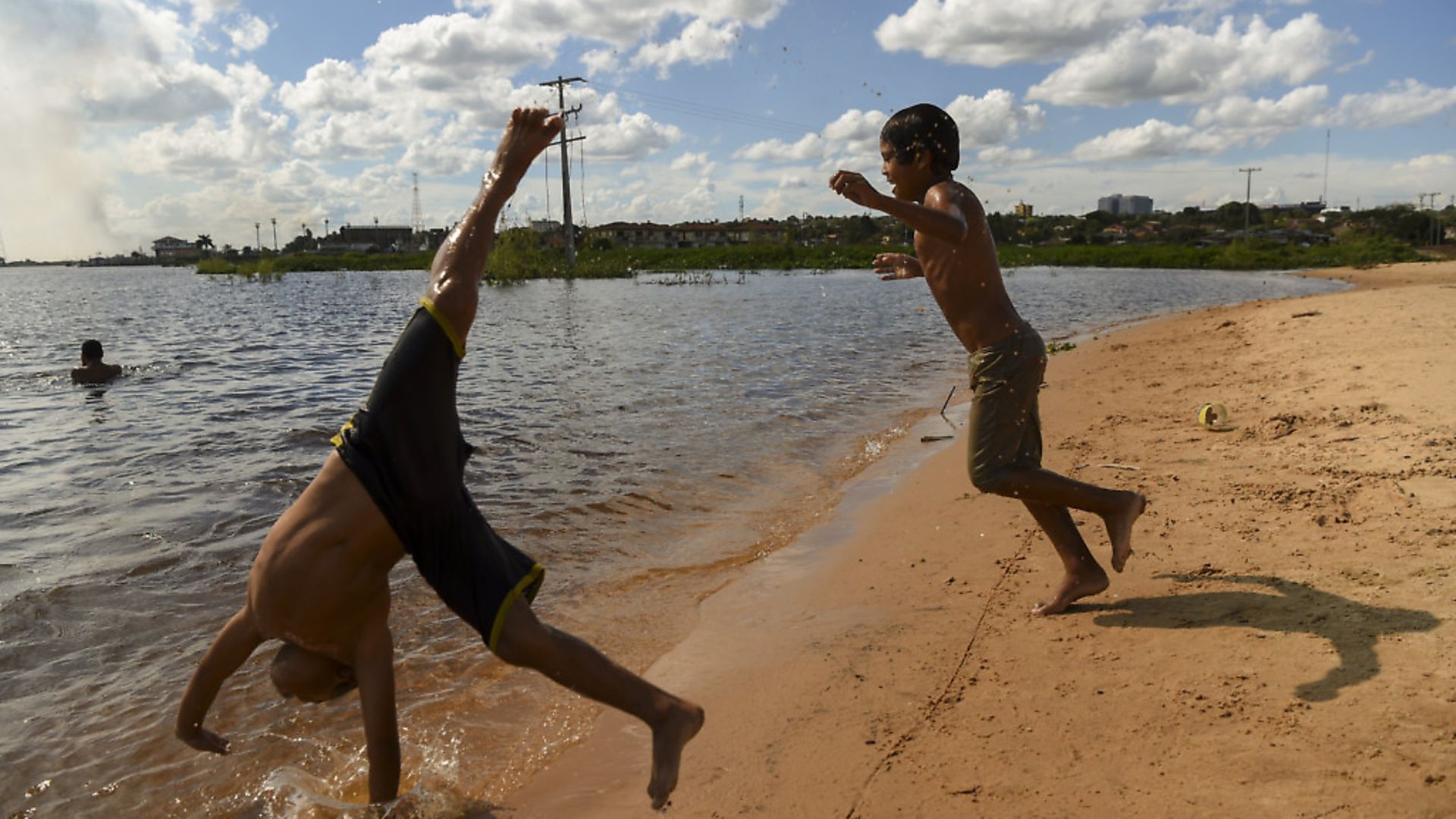 Children play by the shore of the Paraguay river in Asuncion. Photo: EITAN ABRAMOVICH/AFP via Getty Images - Credit: AFP via Getty Images