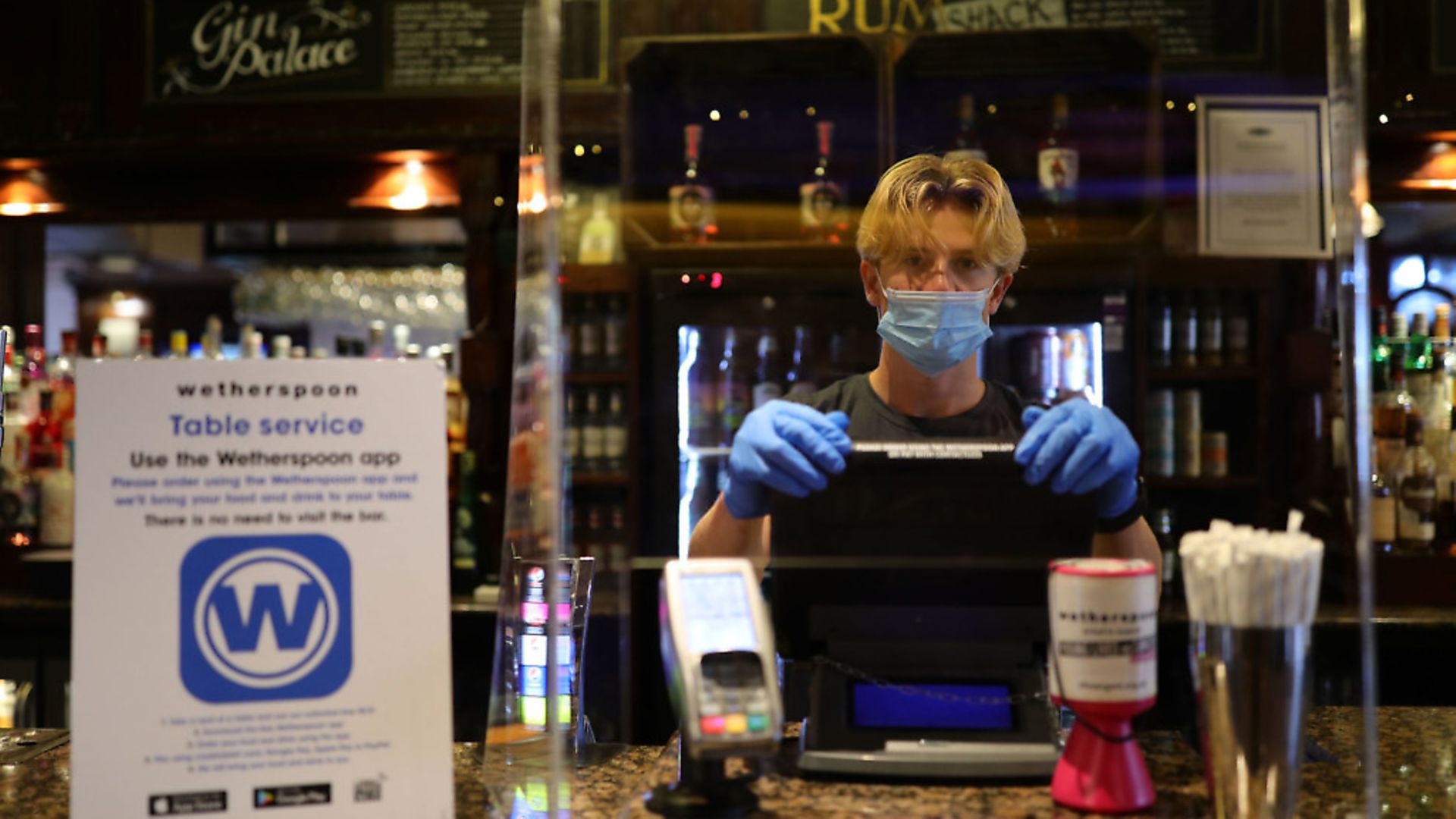 A member of staff in PPE waits to serve drinkers at the reopening of a Wetherspoons pub. Photograph: Aaron Chown/PA Wire. - Credit: PA