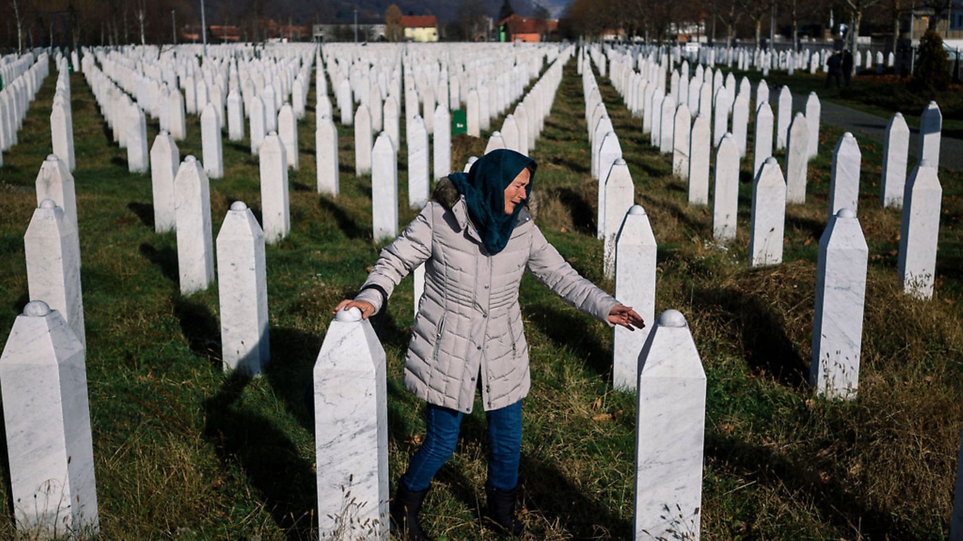 A woman mourns over a relative's grave at the memorial centre of Potocari near Srebrenica in 2017. Photo credit: DIMITAR DILKOFF/AFP via Getty Images - Credit: AFP via Getty Images