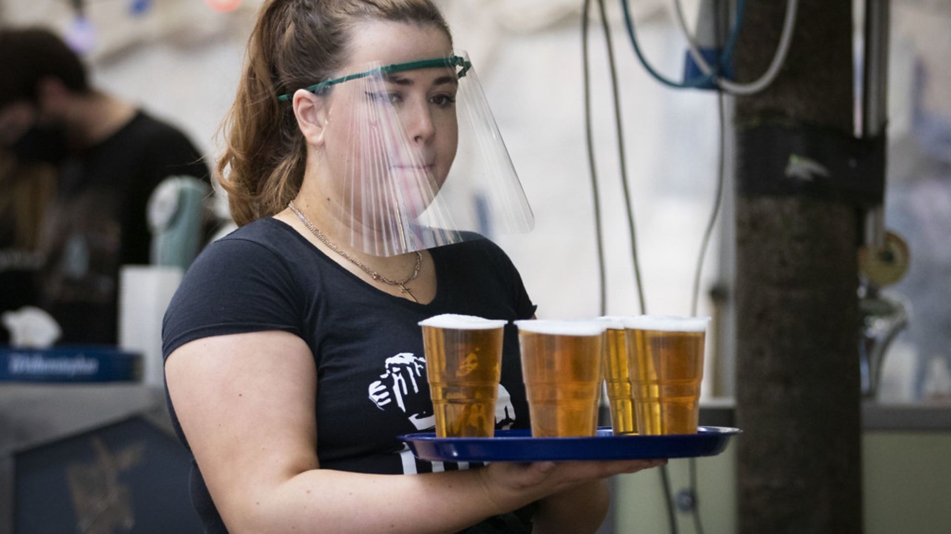 A member of staff serves drinks in a beer garden at a UK pub as they start to reopen - Credit: PA