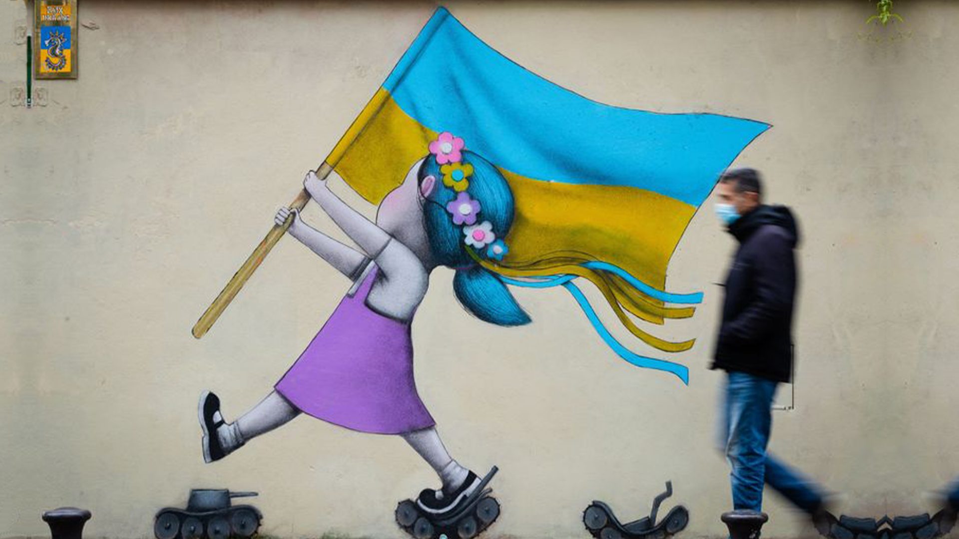 A bystander walks past a fresco by street artist Seth depicting a girl with a Ukrainian flag walking on tanks in Paris. Photo: JOEL SAGET/AFP via Getty Images