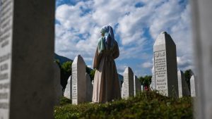 A woman stands in front of a gravestone at the memorial cemetery in the village of Potocari, near Srebrenica, in Bosnia. 
Image: Andrej Isakovic/ AFP/Getty