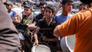 Children queue with pots to receive meals from a charity kitchen in Gaza City. Image: Bashar Taleb/AFP/ Getty