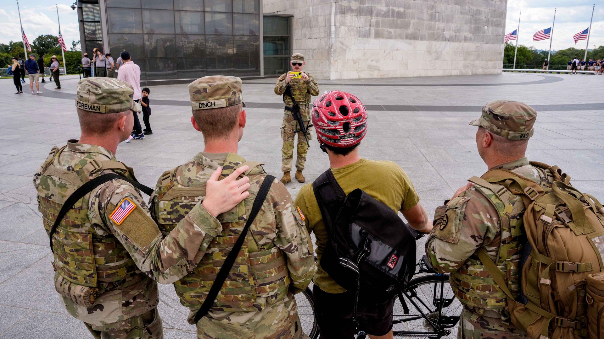 Armed members of the National Guard pose for a photograph with a bicyclist at the base of the Washington Monument on the National Mall. Photo: Andrew Harnik/Getty Images