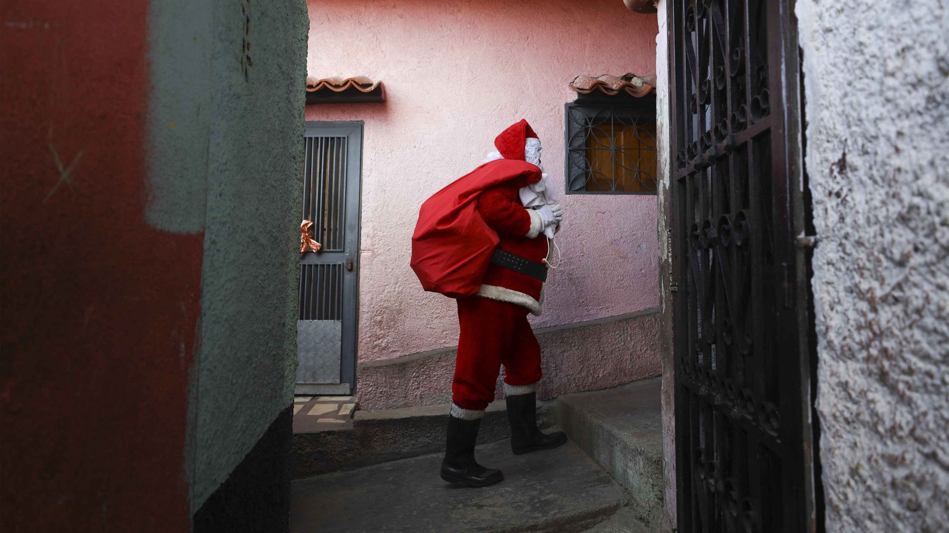 A man dressed as Santa Claus arrives to hand toys to children in a low-income neighborhood known as 'COTA 905', in Caracas. Photo: Pedro Rances Mattey/Anadolu via Getty Images