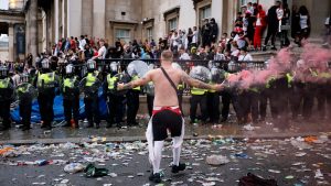 An England fan waves a smoke bomb in front of a line of police officers in Trafalgar Square during a live screening of the Euro 2020 final between England and Italy on July 11, 2021. Image: Tolga Akmen/AFP/Getty