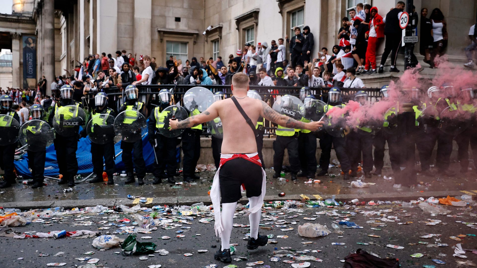An England fan waves a smoke bomb in front of a line of police officers in Trafalgar Square during a live screening of the Euro 2020 final between England and Italy on July 11, 2021. Image: Tolga Akmen/AFP/Getty