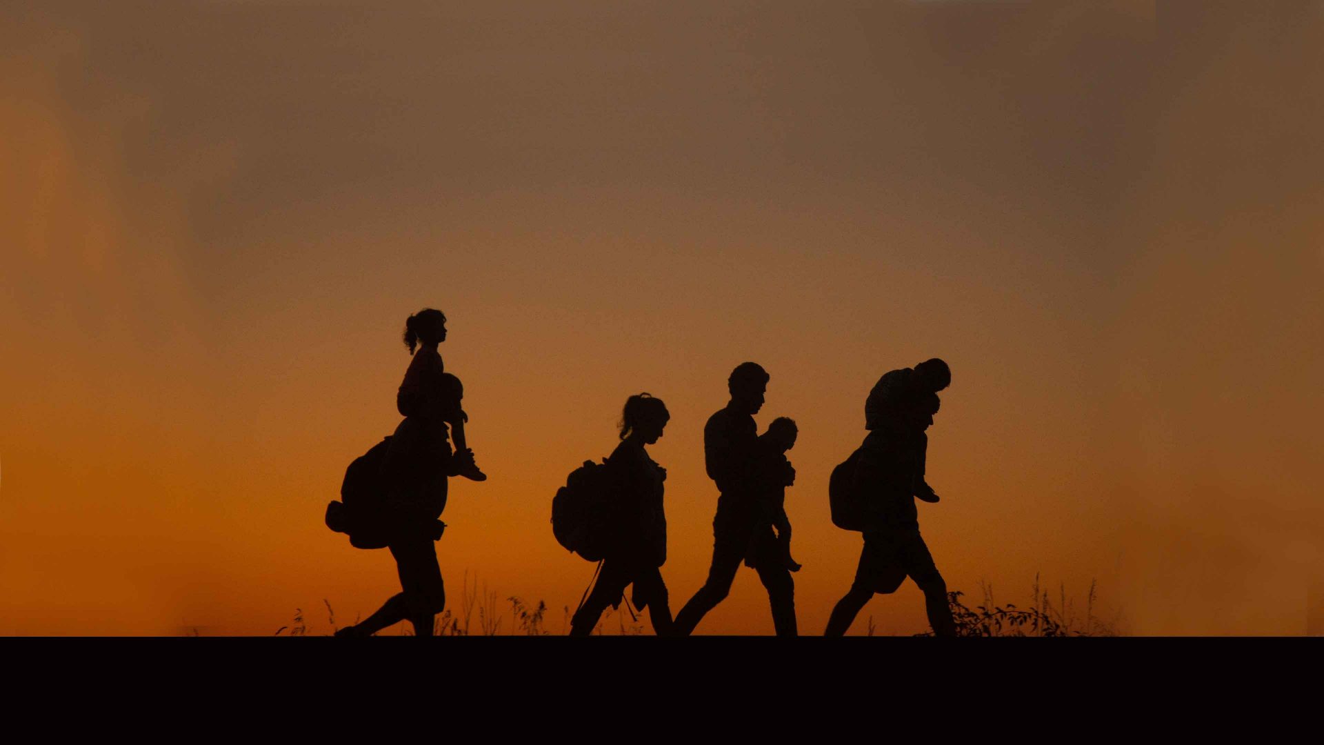 Asylum seekers walk along a railway line   close to the village of Roszke in Hungary. Image: Matt Cardy/Getty