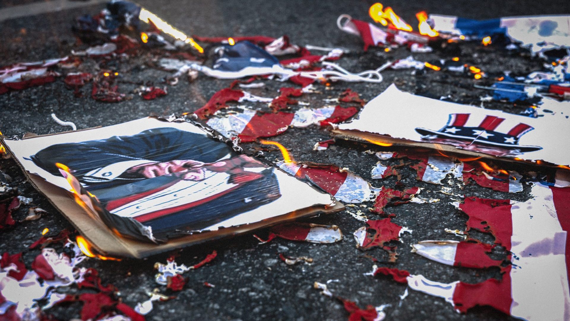 US and Israeli flags and a caricature of Donald Trump lie burnt following a protest outside the US diplomatic mission in Buenos Aires over US interference in Venezuela. Image: ROSANA ÁLVAREZ MULLNER/SOPA/LIGHT-ROCKET/GETTY