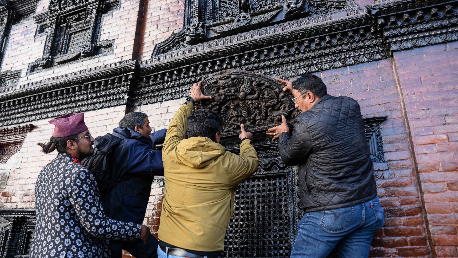 Locals attach the historic toran to its original place above the right-side window of the main entrance of Kumari House in Kathmandu. Photo: Safal Prakash Shrestha/NurPhoto via Getty Images