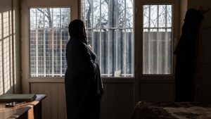 An Afghan hospital medic, who studied public relations and journalism before universities were closed to women, standing next to a window inside a house in Afghanistan. Photo: AFP via Getty Images 