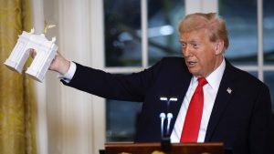 Donald Trump holds a model of an arch as he delivers remarks during a ballroom fundraising dinner in the East Room of the White House. Photo: Kevin Dietsch/Getty Images