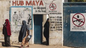 Residents and patients walk past a "no weapons allowed" sign at the entrance of a public hospital in Kismayo. Photo:  SIMON MAINA / AFP via Getty Images