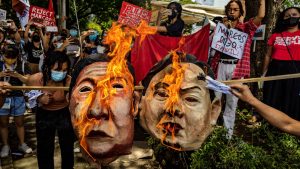Anti-Marcos activists burn an effigy of Ferdinand "Bongbong" Marcos Jr. and Sara Duterte as they take part in a protest against election results at the Commission on Human Rights office. Photo: Ezra Acayan/Getty Images