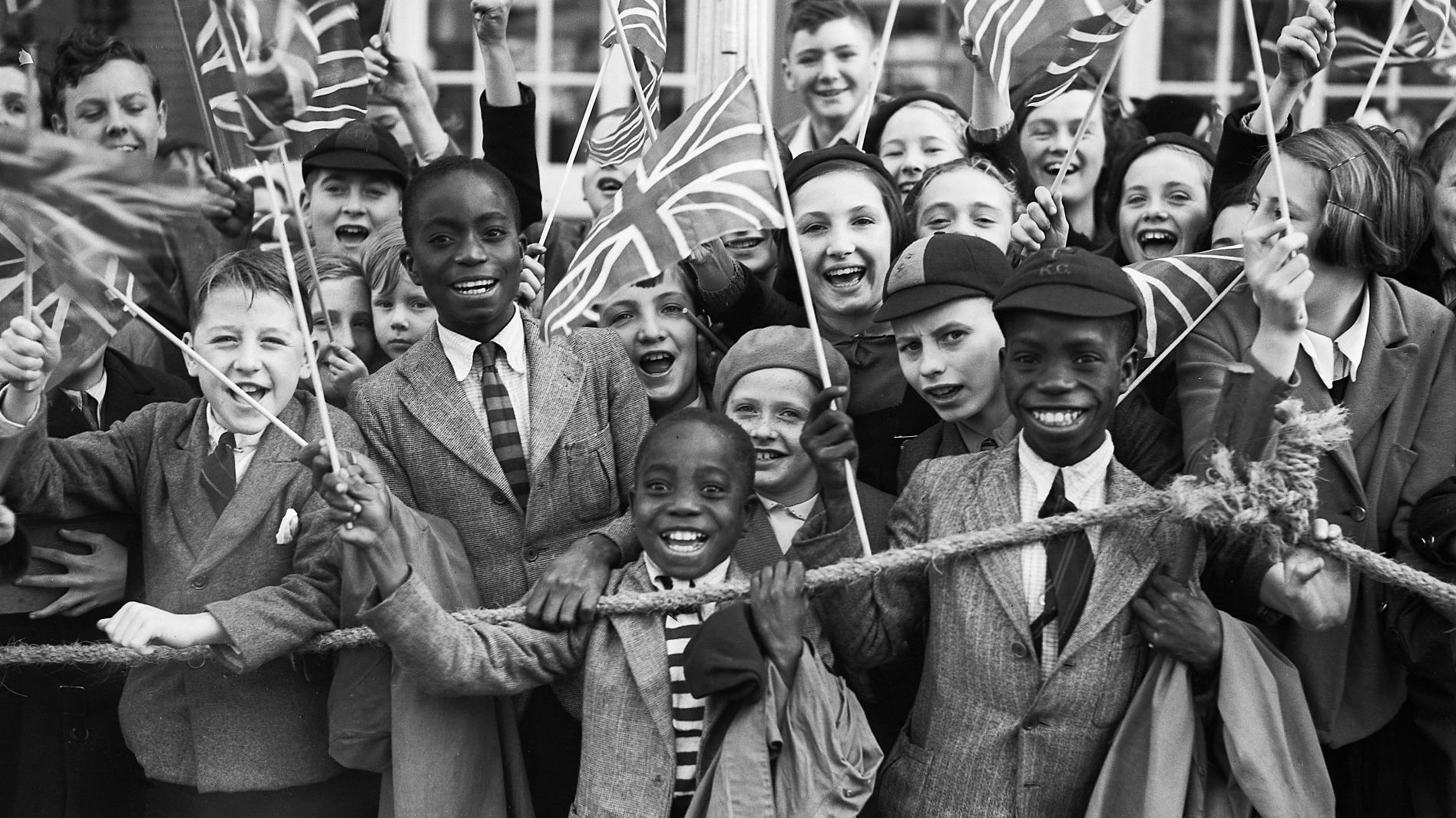 A crowd of children wave union flags as Queen Mary, wife of King George V, visits south London to open the new Lambeth Town Hall, October 1938. Image: Reg Speller/Fox Photos/Hulton Archive/Getty